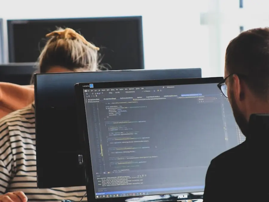 Two engineers reviewing code together on a monitor